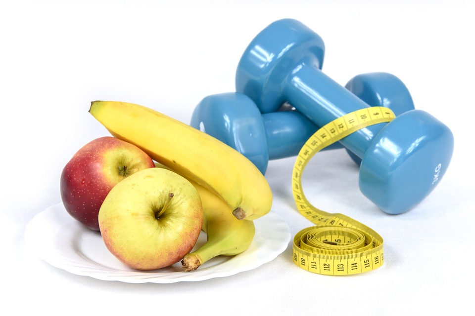 dumbbells, measuring tape and a plate of fruits
